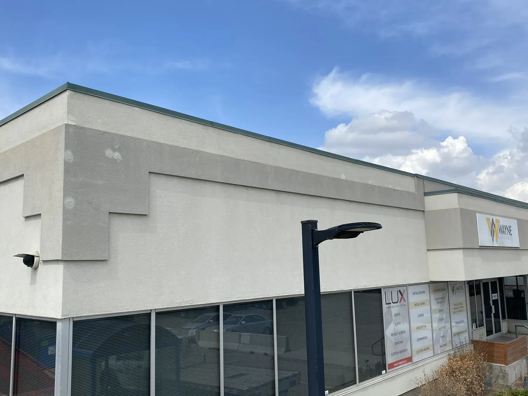 Retail plaza with a repaired EIFS cornice and parapet above a row of storefront windows