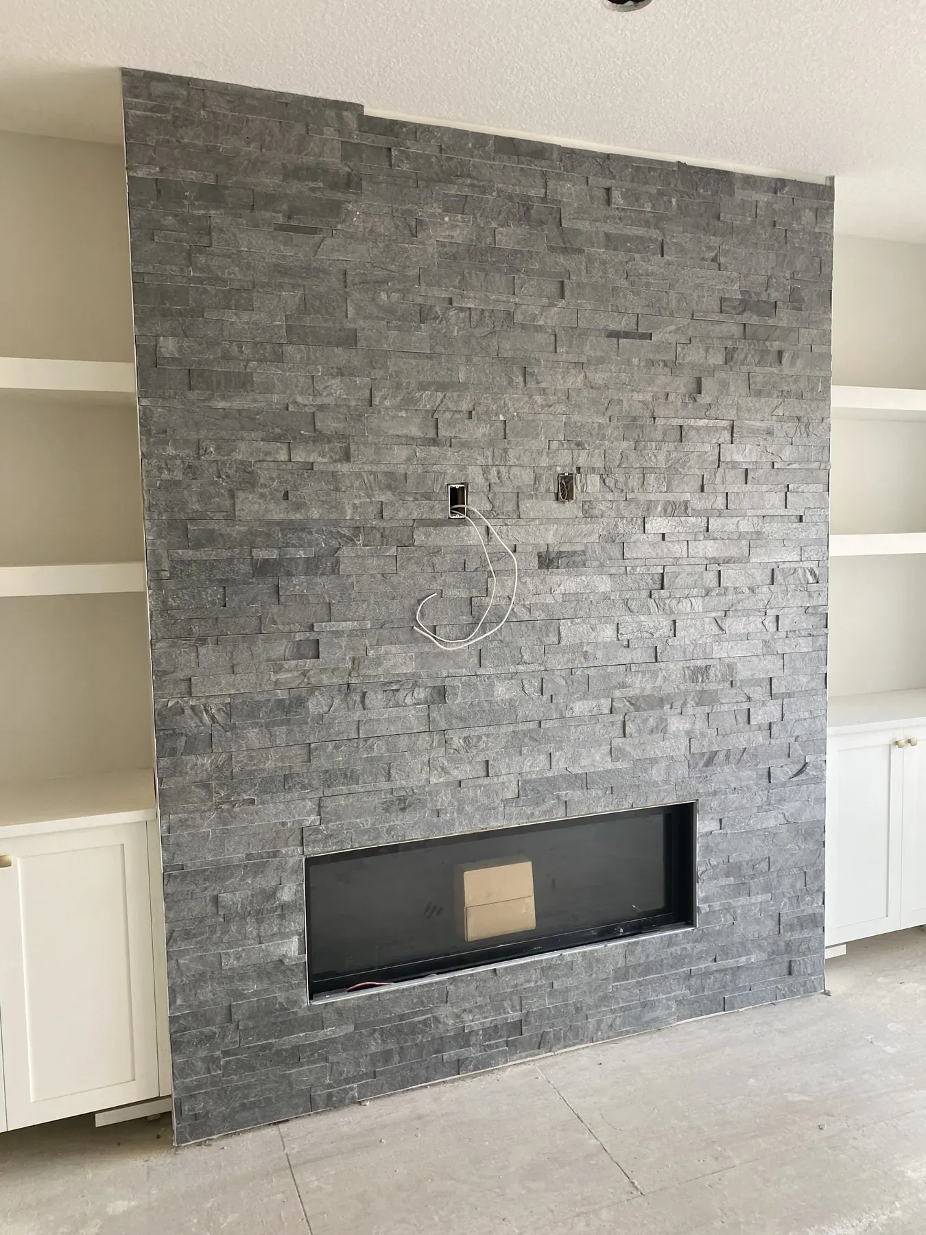 Floor to ceiling stacked stone fireplace feature wall during finishing