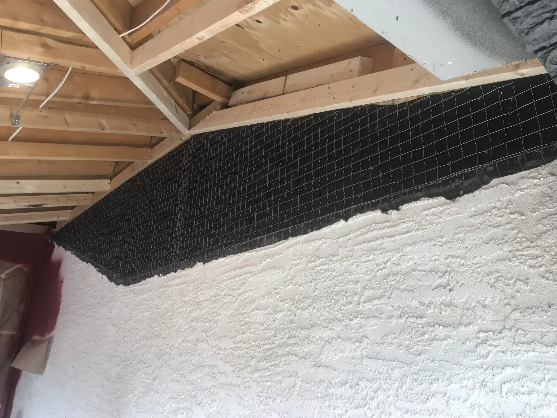 Wire lath and scratch coat going on over a framed garage wall before the stucco finish