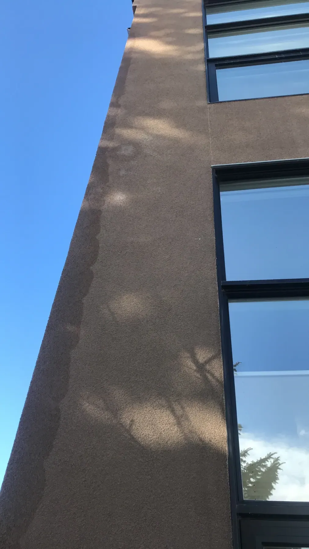 Tall stucco wall with modern black windows